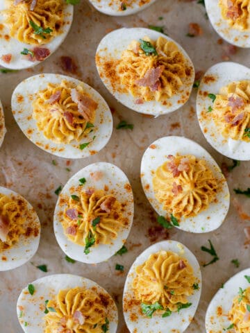 An overview shot of deviled eggs with bacon on a piece of parchement paper